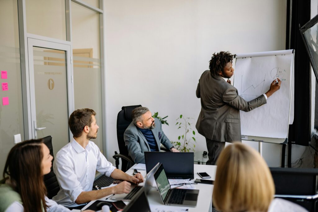 pexels-photo-7794060-7794060 A diverse team in a modern office engaged in a strategic business meeting led by a presenter.
